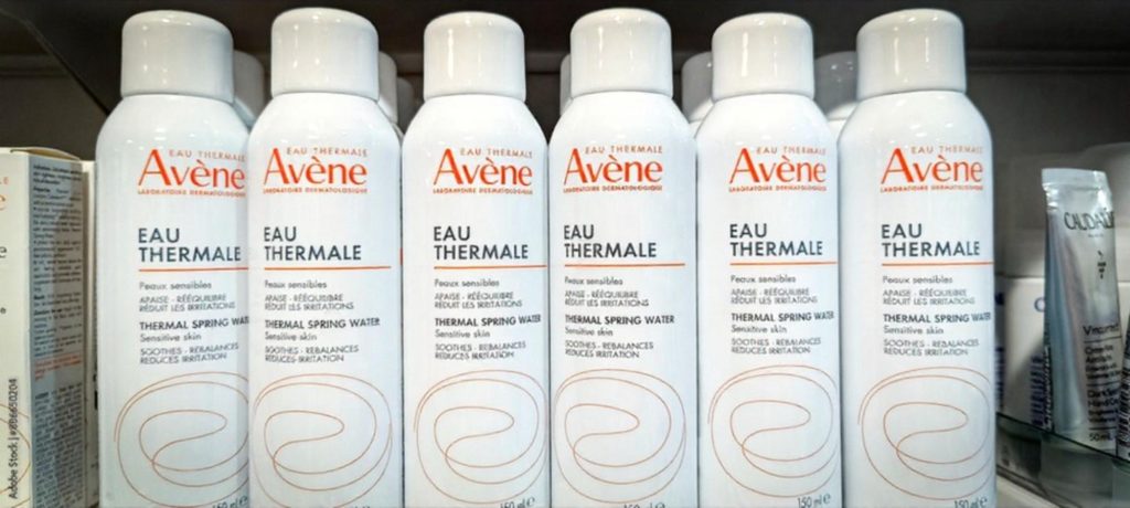Avene thermal spring water spray bottles displayed on a shelf, designed for sensitive skin, featuring soothing and rebalancing properties.