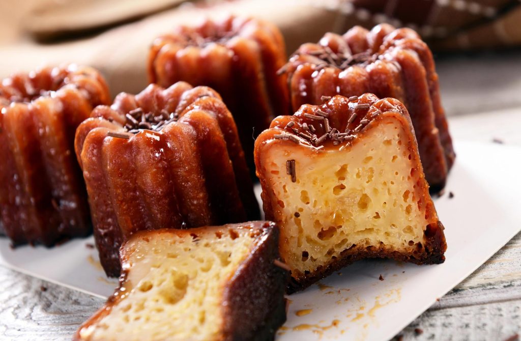 Close-up of canelés, a traditional French pastry, showcasing their caramelized exterior and soft, custard-like interior.