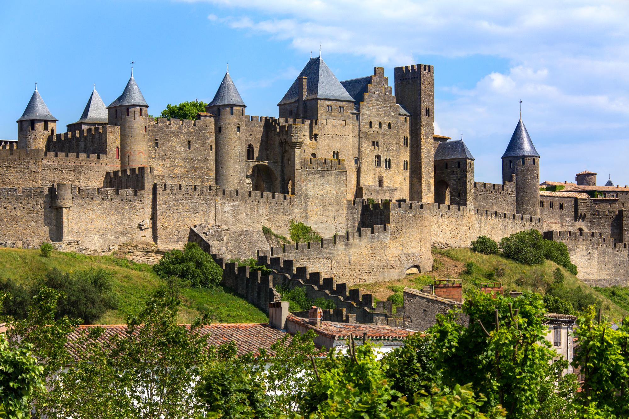 View of the medieval fortress of Carcassonne in France, showcasing its towers and walls against a blue sky.
