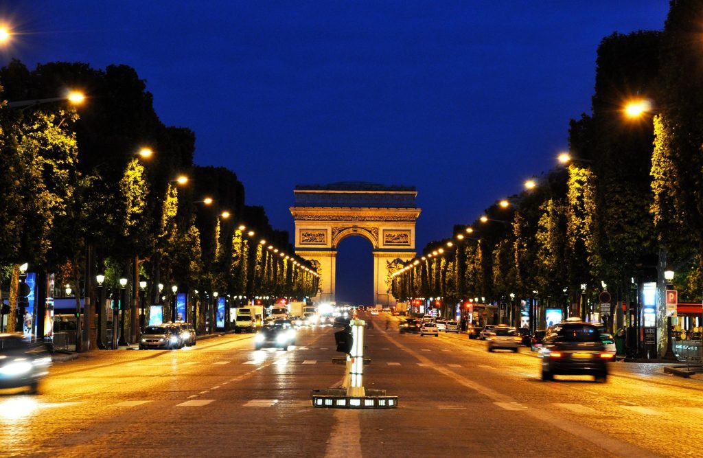 Night view of the Champs-Élysées avenue with the Arc de Triomphe illuminated in the background.