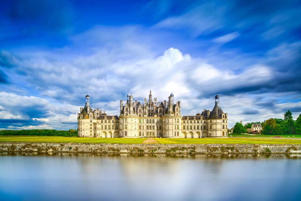 A beautiful view of Château de Chambord with its distinctive towers and ornate architecture reflected in the tranquil waters of the surrounding landscape.
