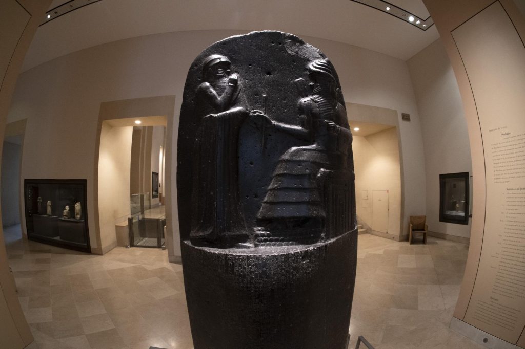The Code of Hammurabi, an ancient Babylonian artifact depicting a ruler receiving laws from a deity.