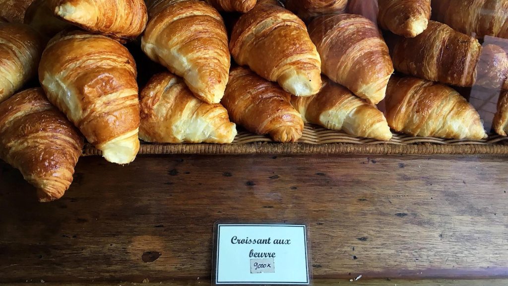 A display of freshly baked buttery croissants in a wooden basket.