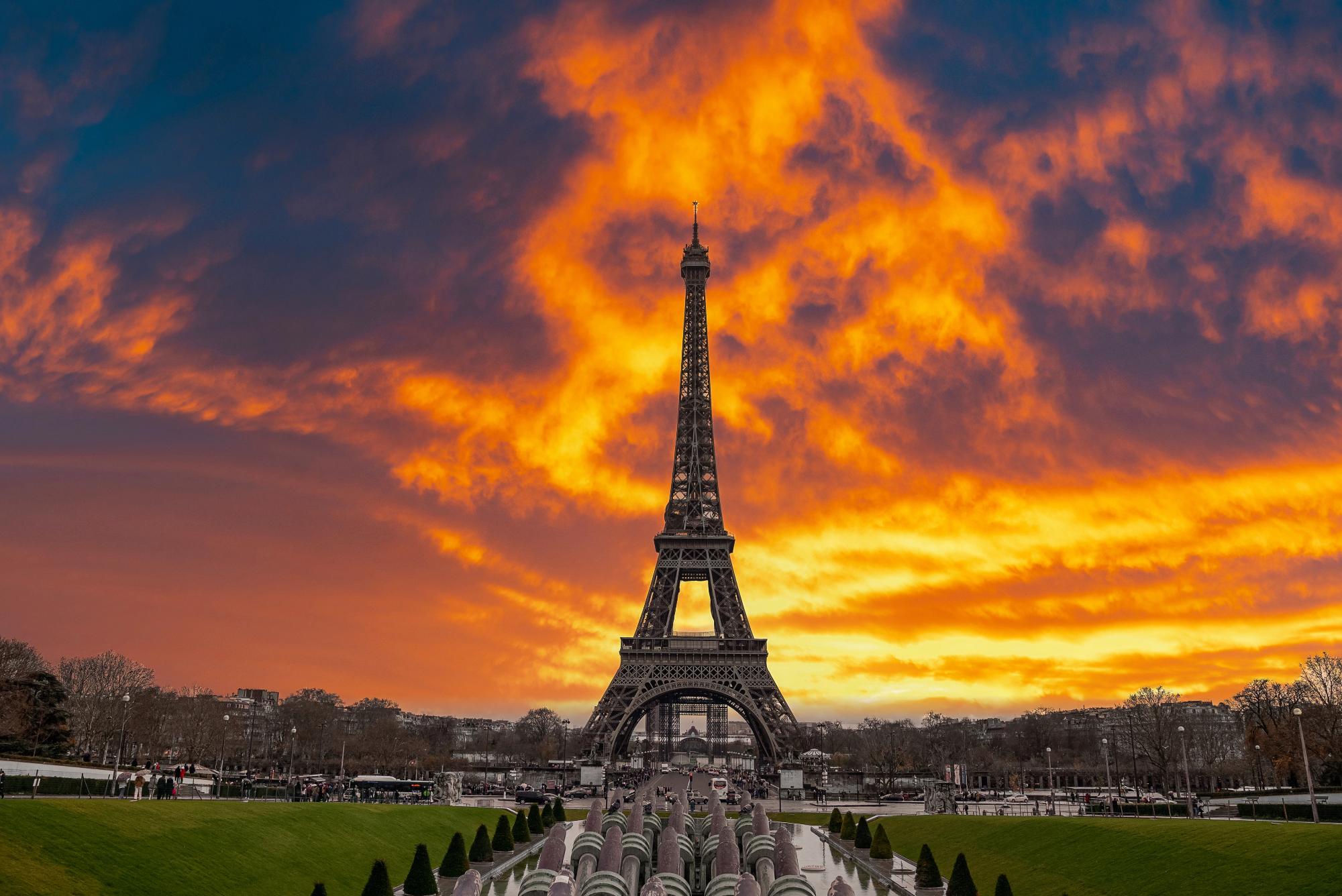 A stunning view of the Eiffel Tower against a vibrant sunset sky filled with dramatic clouds in Paris.
