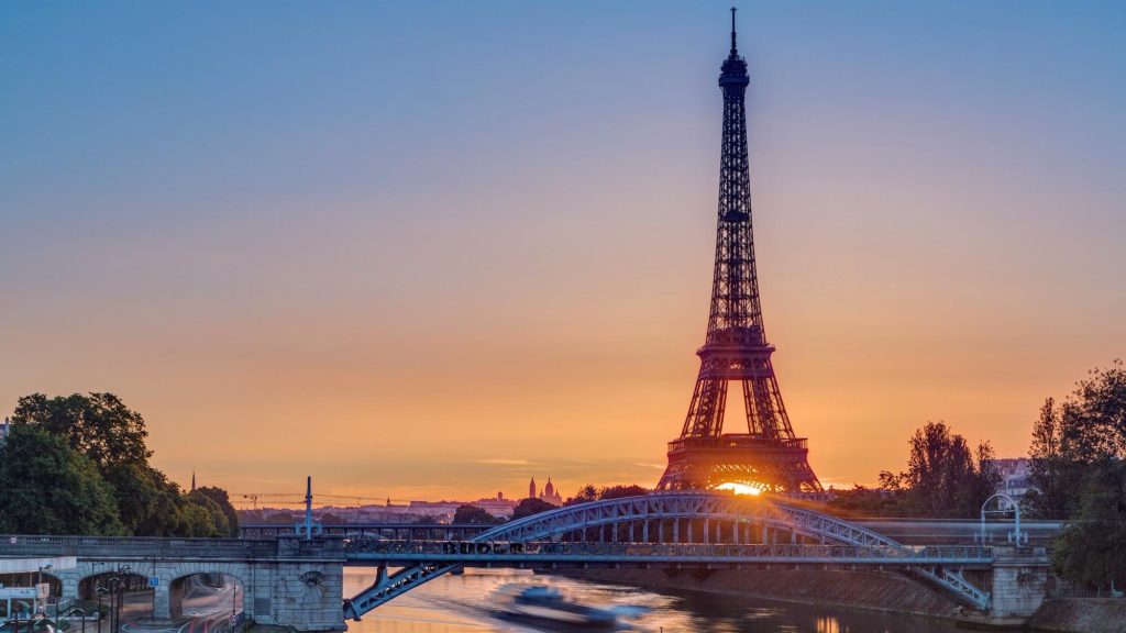 Sunrise timelapse of the Eiffel Tower with boats on the Seine River, viewed from Grenelle Bridge in Paris, France.
