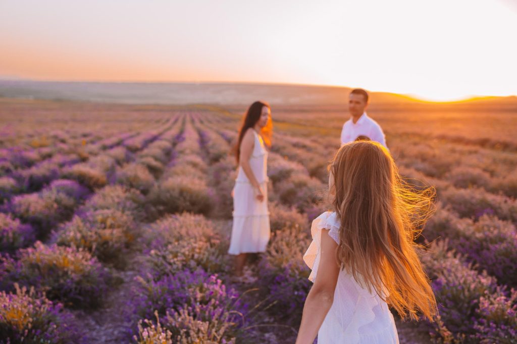 A family enjoying time together in a lavender field during sunset, with beautiful purple flowers surrounding them.