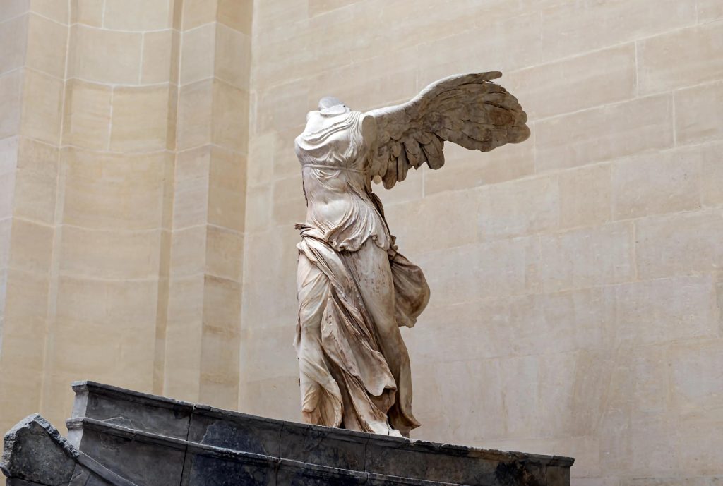 The Winged Victory of Samothrace is a renowned Hellenistic sculpture depicting a winged female figure standing on a ship's prow, showcasing intricate drapery and dynamic posture.