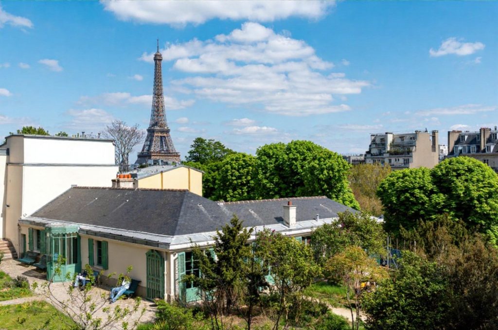 View of Balzac's house with the Eiffel Tower in the background surrounded by greenery and a clear blue sky.