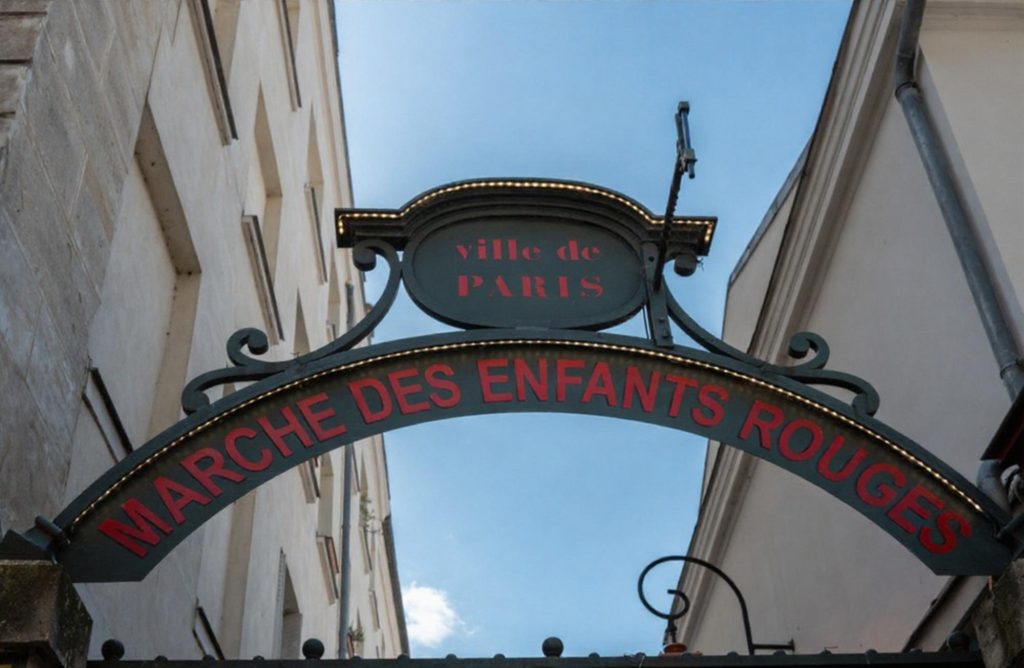 The entrance sign of Marché des Enfants Rouges in Paris, featuring decorative elements and vibrant colors.