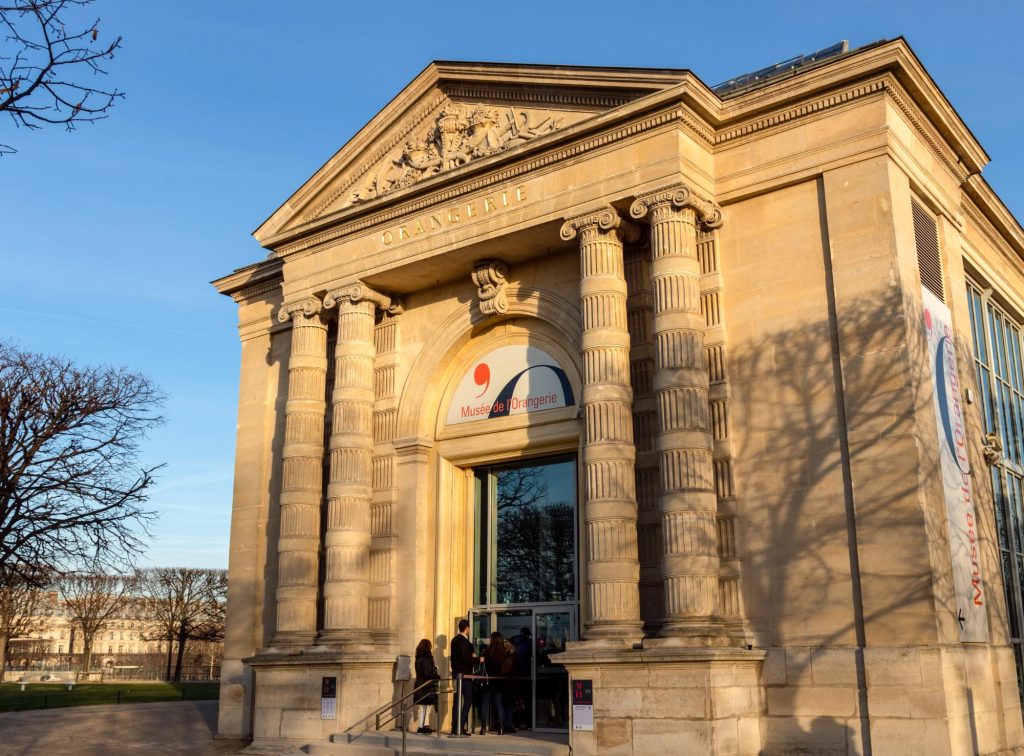 Entrance of the Musée de l'Orangerie in Paris, featuring classical architectural details and visitors waiting outside.