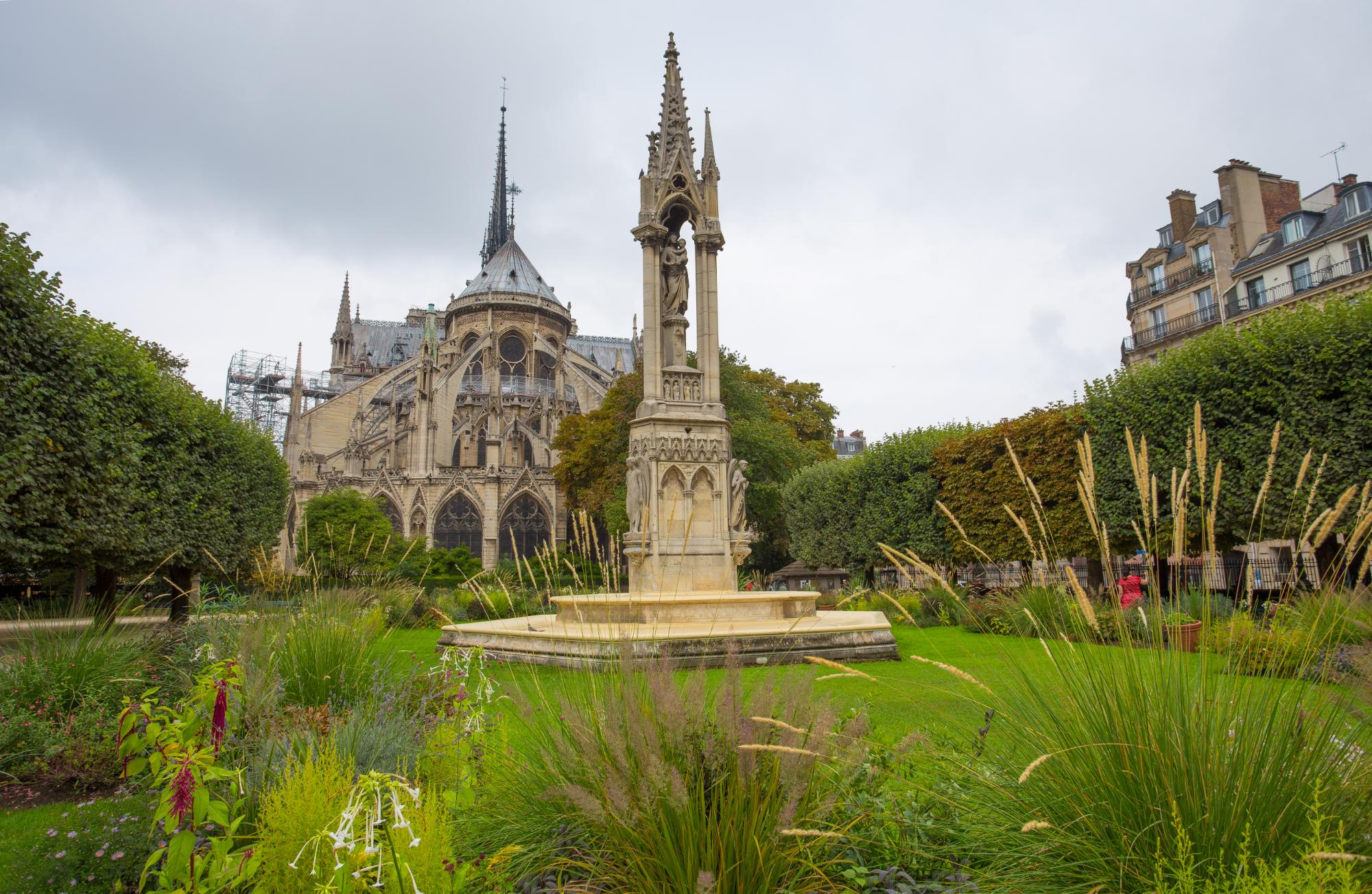 The apse of Notre-Dame Cathedral and the Virgin Fountain in Place Jean-XXIII, Paris, France.