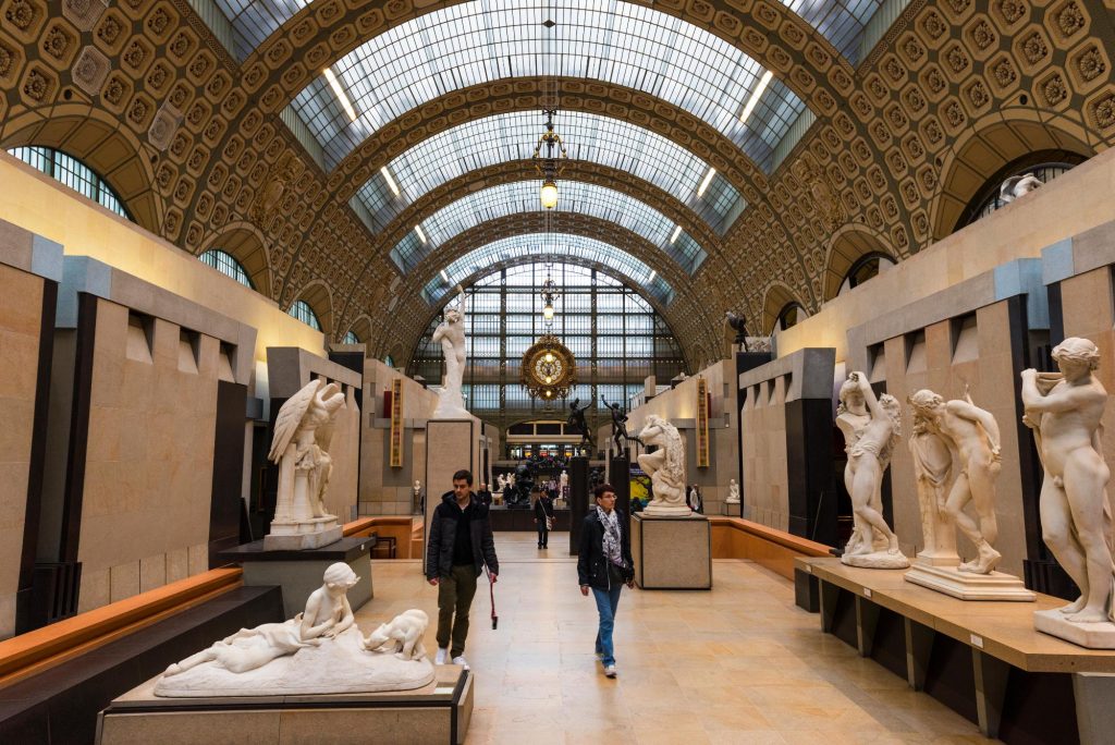 Interior view of the Orsay Museum showcasing various sculptures and a stunning architectural ceiling.