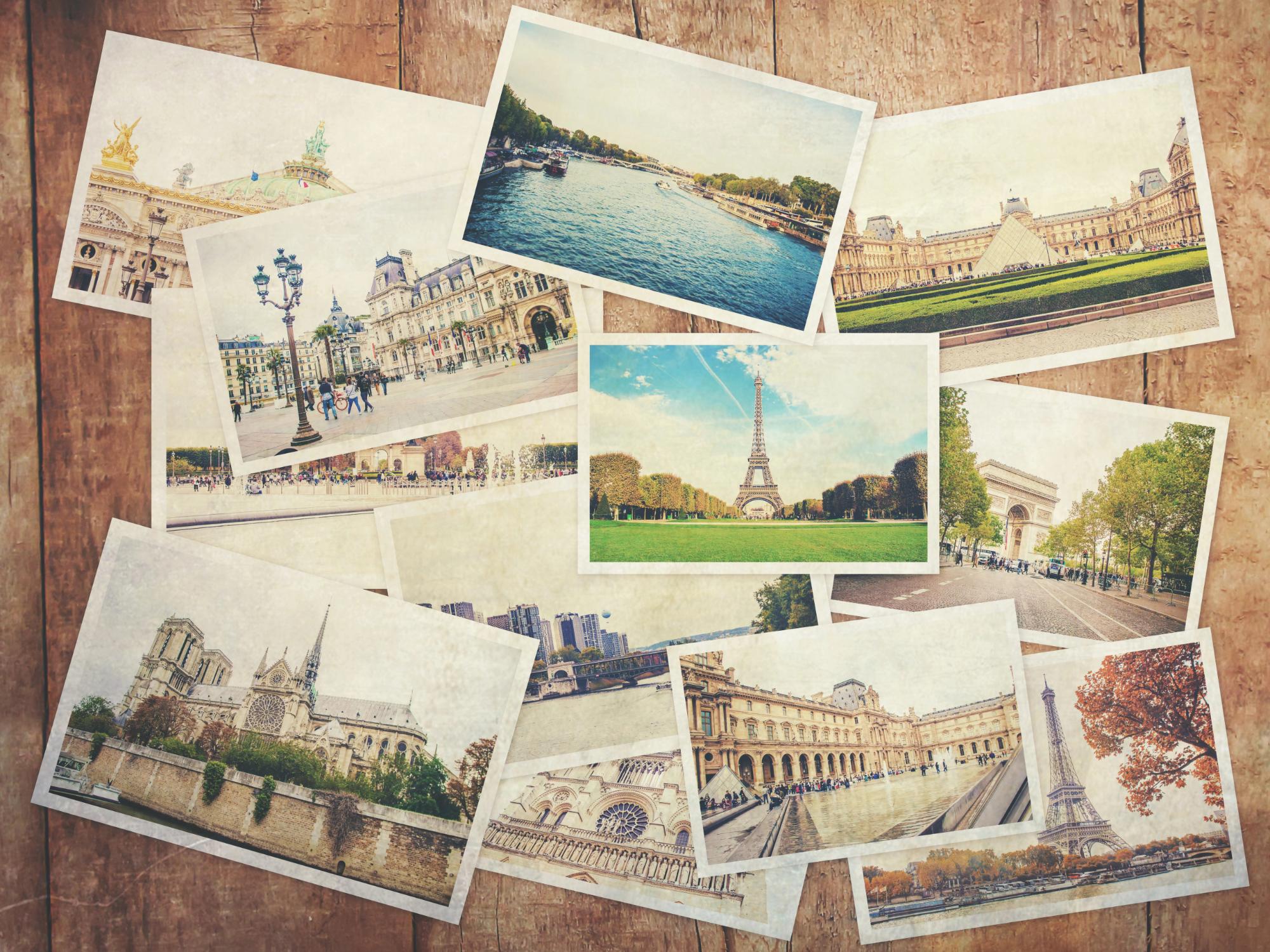 A collection of vintage-style postcards featuring famous landmarks in Paris, including the Eiffel Tower, the Louvre, Notre Dame, and the Arc de Triomphe, arranged over a wooden background.