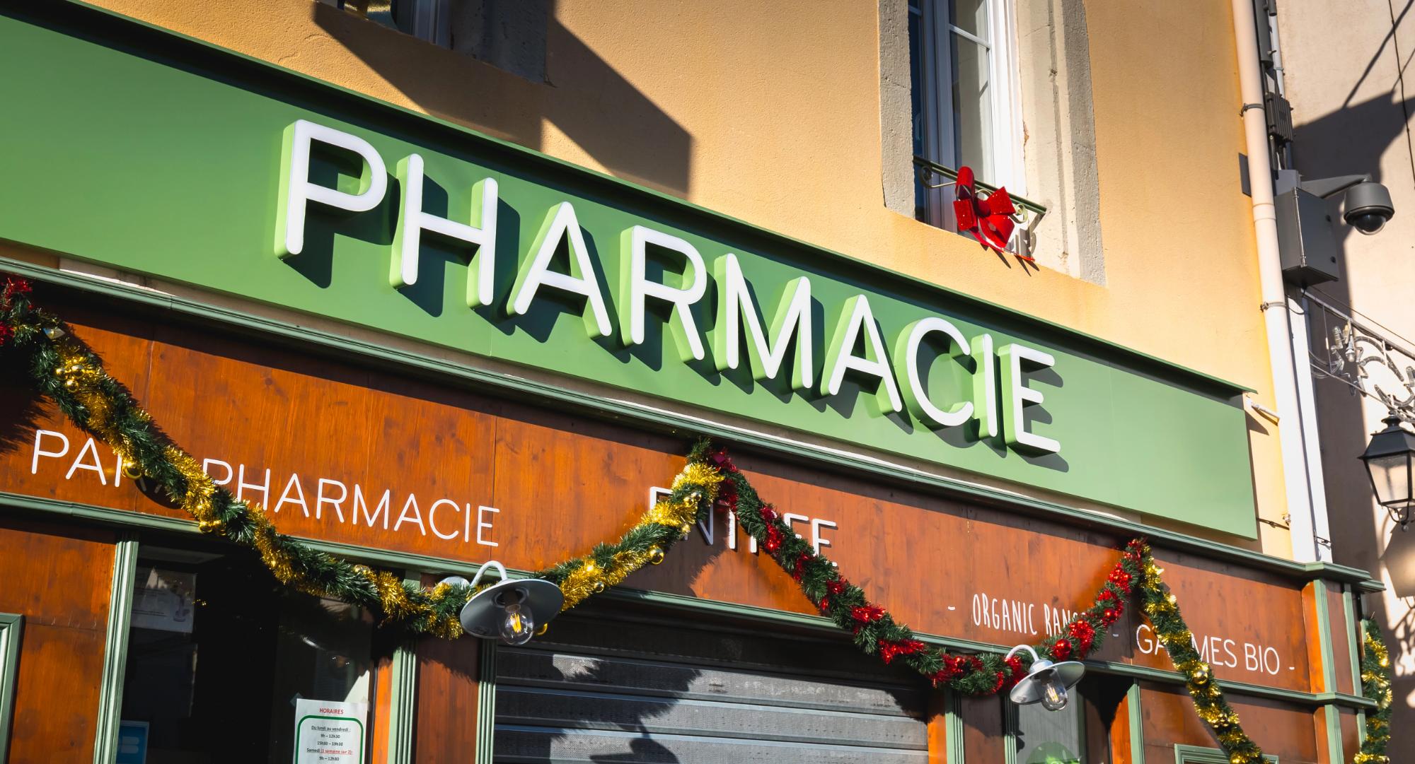 Decorative pharmacy sign with green background and holiday decorations in front