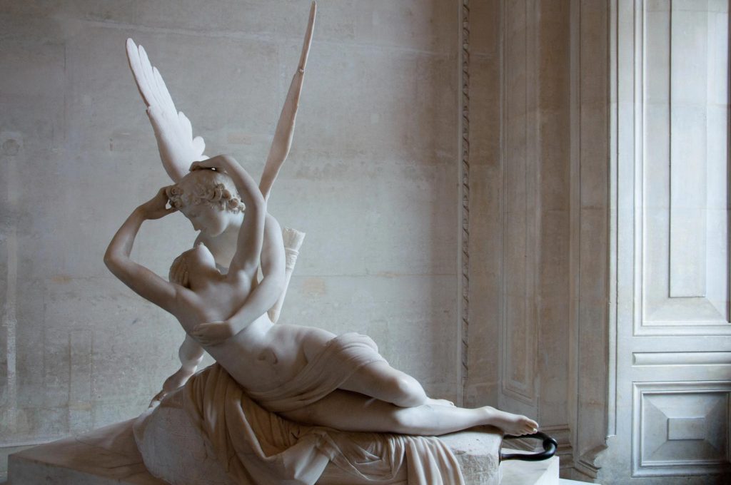 A marble sculpture depicting Psyche being revived by the kiss of Love, showcasing intricate detailing and dynamic poses.