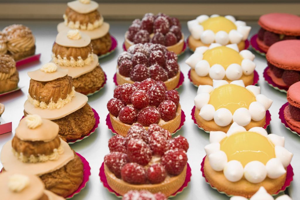 A display of raspberry tartlets with powdered sugar, lemon tartlets, and colorful French macaroons.