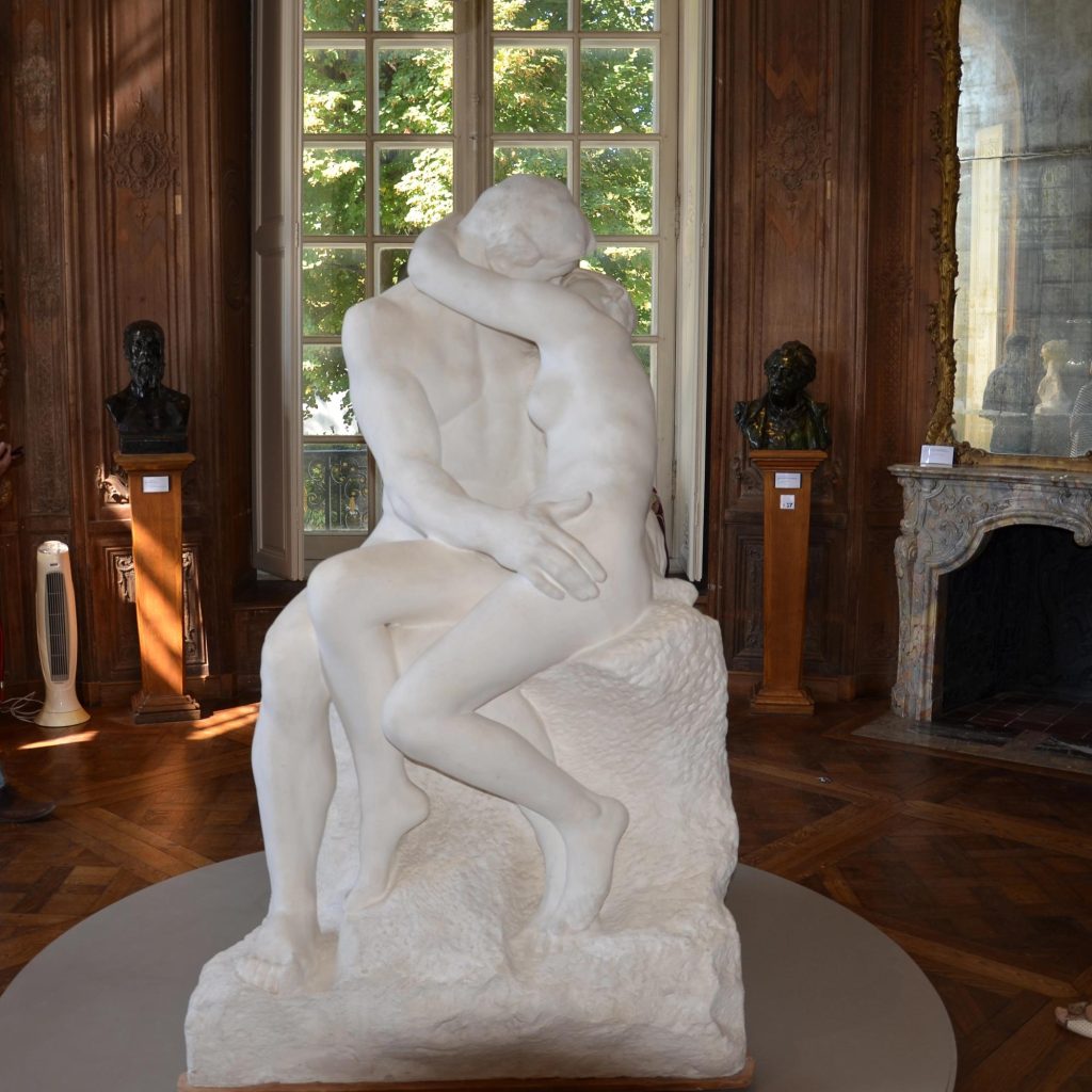 A white marble sculpture depicting a couple in an intimate embrace, showcasing their love and connection.