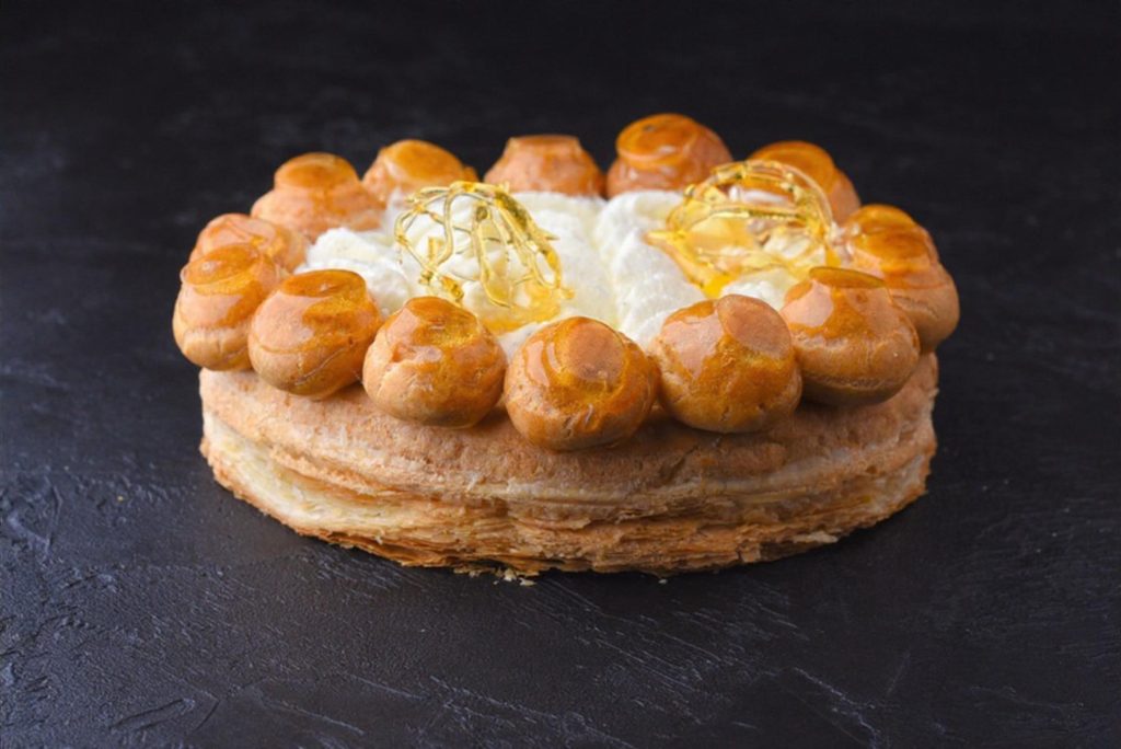 a round Saint-Honoré pastry topped with cream and caramelized choux pastry balls