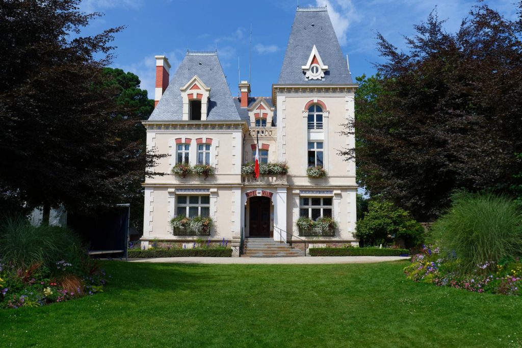 Beautiful town hall building with flower beds and greenery under a blue sky.