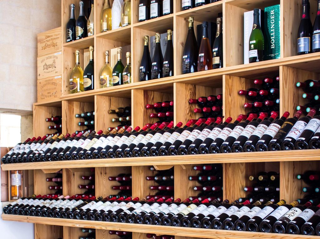 A variety of wine bottles neatly arranged on wooden shelves, featuring both red and sparkling wines.