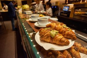 French baked croissants sprinkled with icing or powered sugar on wooded table background.