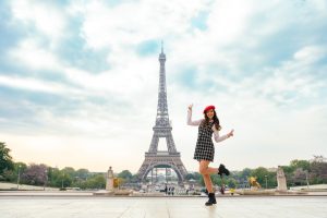 Beautiful young woman visiting paris and the eiffel tower. Parisian girl with red hat and fashionable clothes having fun in the city center and landmarks area