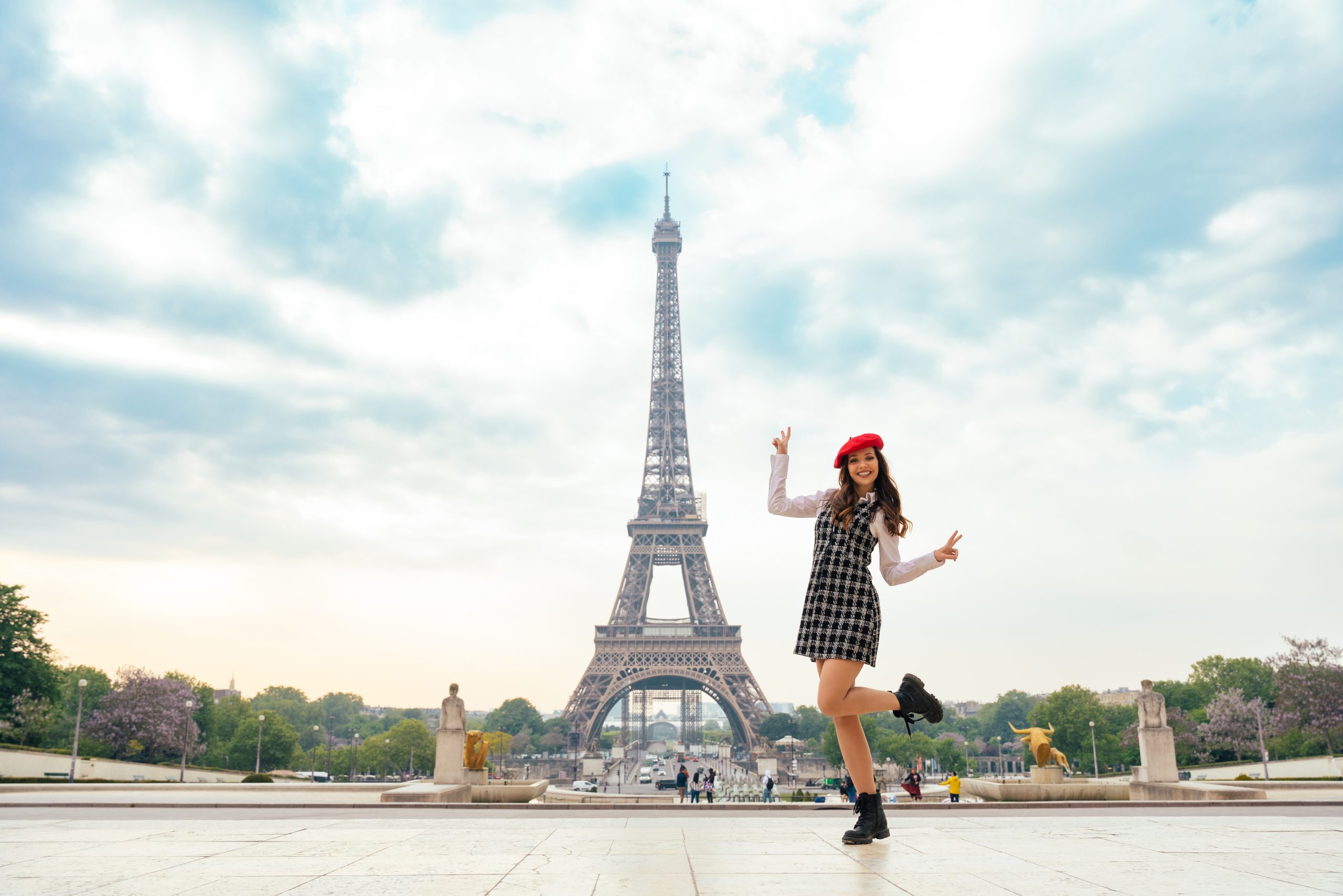 Beautiful young woman visiting paris and the eiffel tower. Parisian girl with red hat and fashionable clothes having fun in the city center and landmarks area