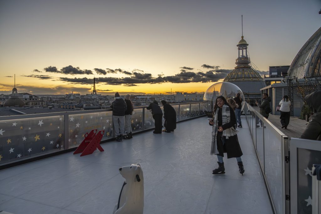Paris,France - 11 20 2025: Le Printemps Store: View of ice skaters on the rooftop of Le Printemps Store on the ephemeral Christmas ice skating rink at sunset