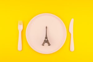 Small Eiffel tower love symbol plate serving plastic tableware copy space on bold yellow background in creative minimal style. Concept Valentine love holiday travel feminine blog social media