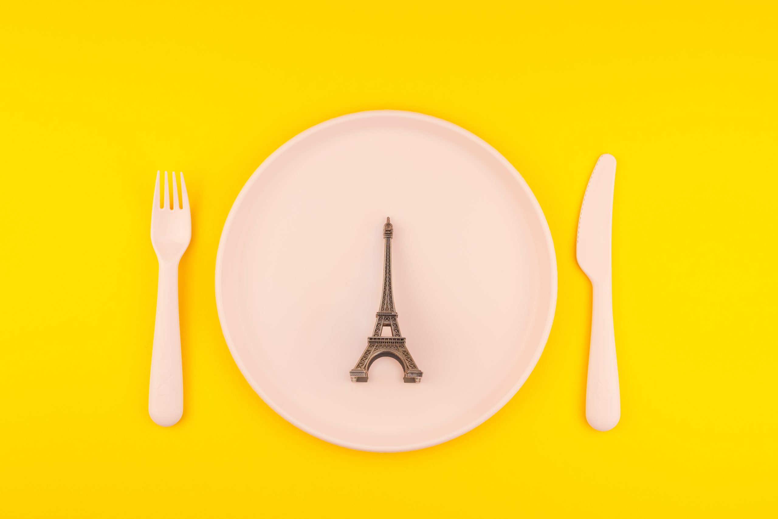 Small Eiffel tower love symbol plate serving plastic tableware copy space on bold yellow background in creative minimal style. Concept Valentine love holiday travel feminine blog social media