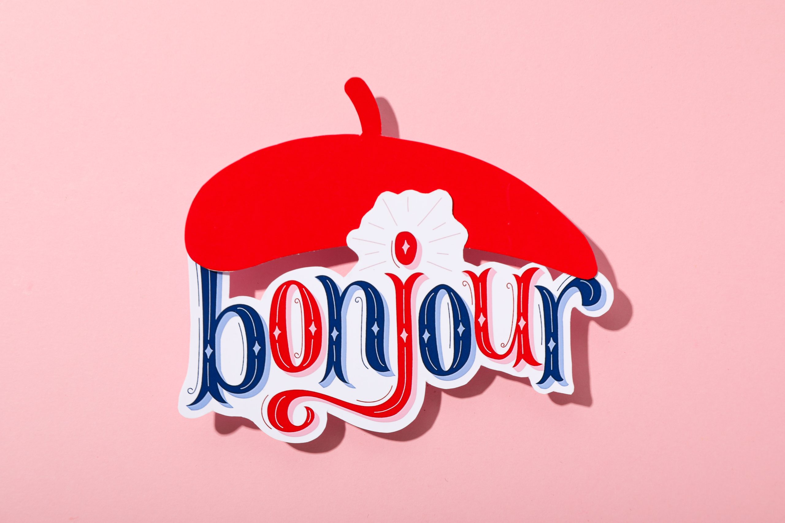 The word "bonjour" with a beret on a pink background.