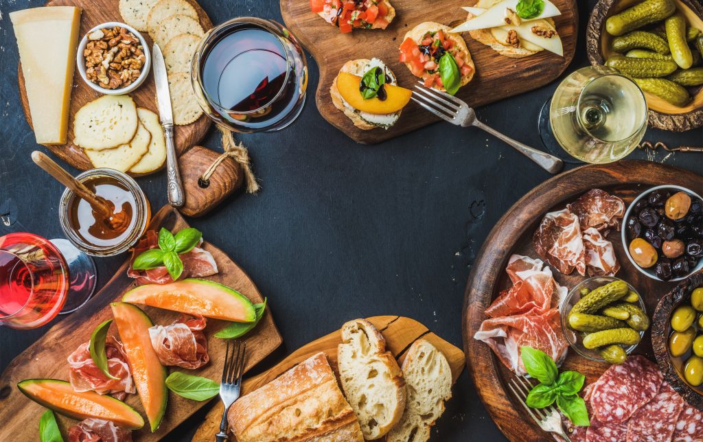 wine antipasti snack variety over dark background, top view, copy space, horizontal composition