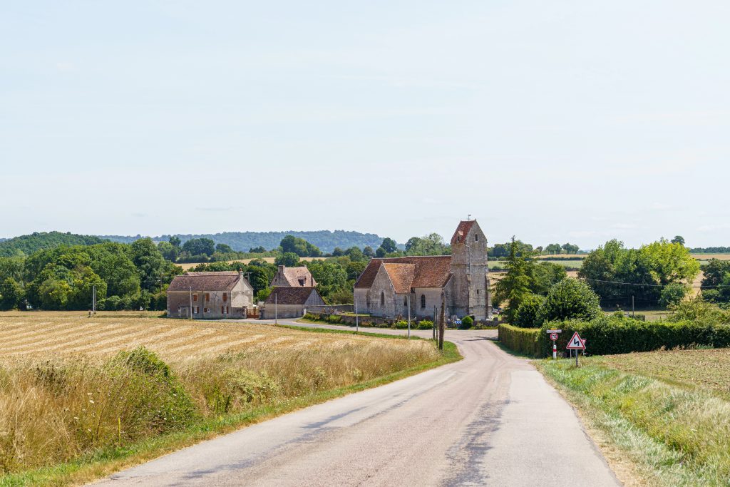 A rural road with a church and a few houses in France Normandy.