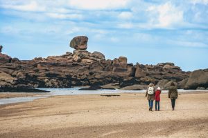 Family walks by typical Brittany coast at the Tregastel in the north of France.
