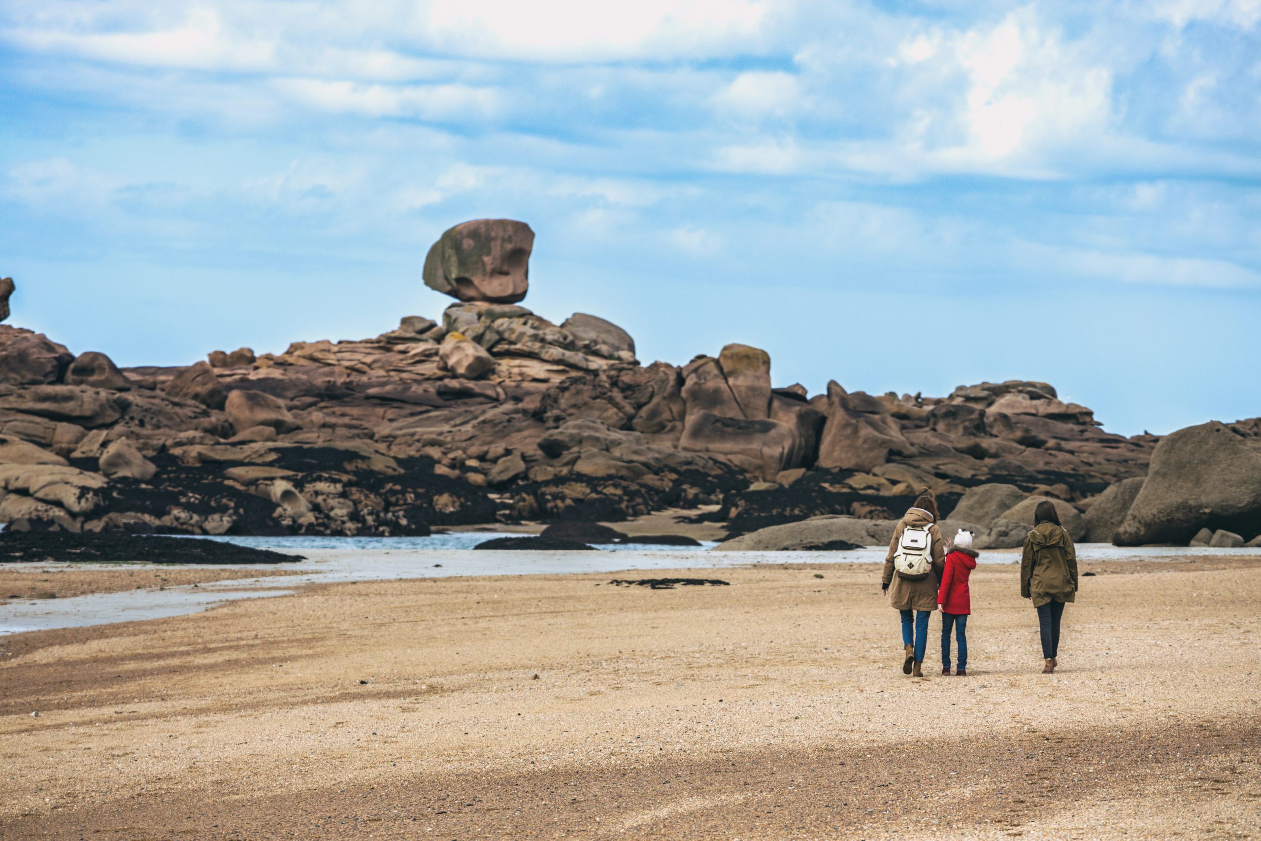 Family walks by typical Brittany coast at the Tregastel in the north of France.