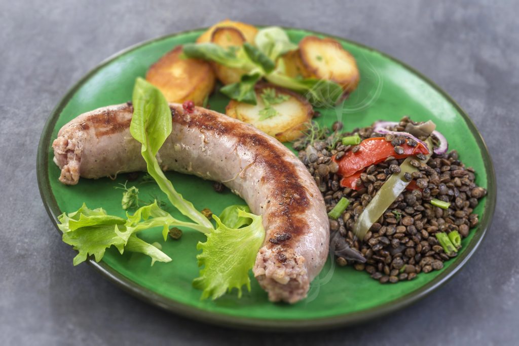 France Grilled Toulouse sausage with roasted potatoaes and salad and lentils on old wooden background